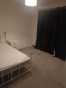 a bedroom with a bed and a black curtain at Falcon Drive Room 1 in Oldham