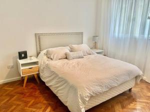 a bedroom with a white bed with a wooden floor at flat in Buenos Aires in Buenos Aires