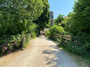 a dirt road with a fence and flowers at Moulin de la Rouchotte in Frétigney-et-Velloreille