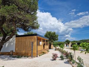 a small wooden cabin with a tree and flowers at Beach House Mane Sol - Perfect Seafront House For Relaxing Holidays in Drage