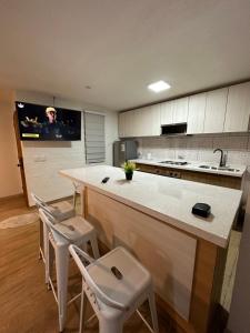 a kitchen with a counter and two stools and a tv at Casa con Jacuzzi in San Pedro de la Paz