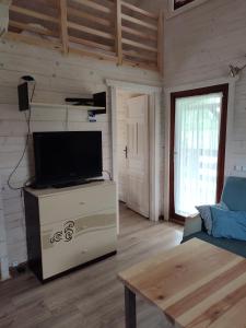 a living room with a flat screen tv on a dresser at Domki na zaciszu w Rynie in Ryn
