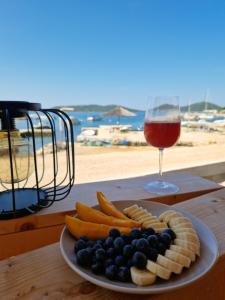 a plate of fruit and vegetables and a glass of wine at Beach House Mane Sol - Perfect Seafront House For Relaxing Holidays in Drage