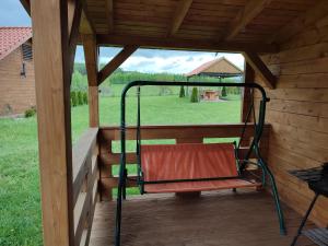 a swing on a porch with a view of a field at Domki na zaciszu w Rynie in Ryn