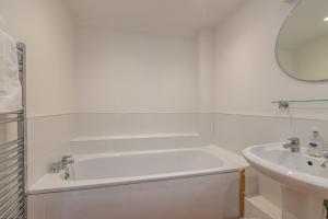 a white bathroom with a tub and a sink at The Dairy in Beaminster