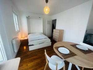 een kamer met een tafel en stoelen en een bed bij studio cosy face à la gare in Lorient
