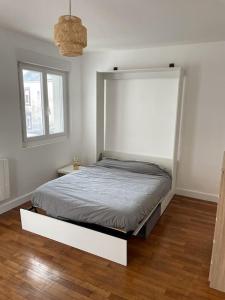 een bed in een witte kamer met een raam bij studio cosy face à la gare in Lorient