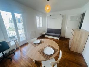 uma sala de jantar com uma mesa e cadeiras num quarto em studio cosy face à la gare em Lorient