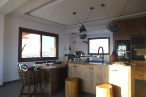 a kitchen with wooden cabinets and two windows at Villa Ktima Lipsi - Jacuzzi & Stunning Sea Sunsets in Klouvas