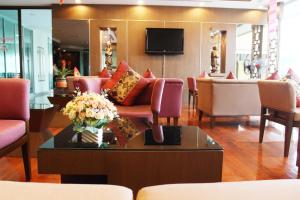 a lobby with chairs and a table with a vase of flowers at Noppakao Place in Chiang Mai