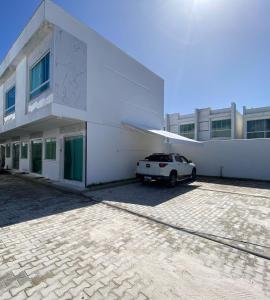 un edificio blanco con un coche aparcado delante de él en APT DUPLEX BEST BIGGEST ENCANTOS de TAPERAPUAN a 100 M da PRAIA, en Porto Seguro
