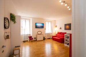 a living room with a red couch and two windows at PortaTorre Suite, a Charming apartment in the Heart of Como, Free Private Parking, Air Conditioning & More! in Como +55 photos