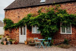 una casa de ladrillo con sillas y una mesa frente a ella en The Coach House Barn en Shrewsbury