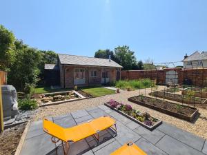 un patio trasero con un banco amarillo y un jardín en Dragonfly cottage en Christchurch