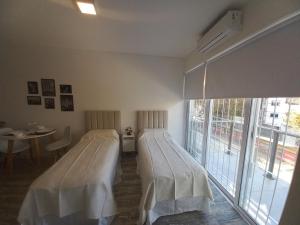 ブエノスアイレスにある@juanbjustoapartamentoのベッド2台、テーブル、窓が備わる客室です。