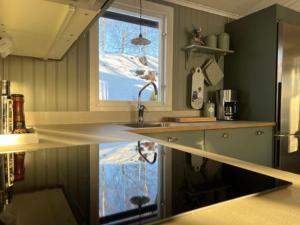 a kitchen with a sink and a window with snow at Sommarstuga med sjötomt och brygga in Hedemora