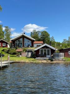 a house on the shore of a body of water at Sommarstuga med sjötomt och brygga in Hedemora