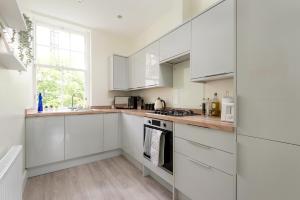una cucina bianca con mobili bianchi e una finestra di The Tron Square Residence a Edimburgo
