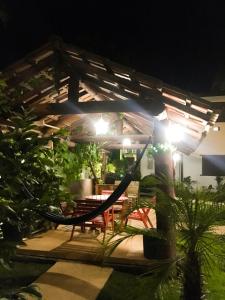 a patio at night with a hammock and a table at Pousada das Estrelas in Itaúnas