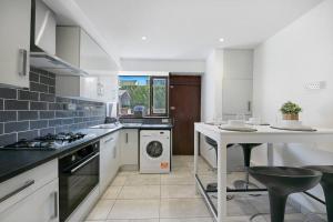 a kitchen with a stove and a sink and a dishwasher at Faulds Crescent Lodge ✪ Grampian Lettings Ltd in Aberdeen