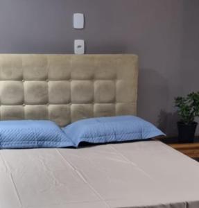 um quarto com uma cama grande e almofadas azuis em Casa no Moradas em Pelotas