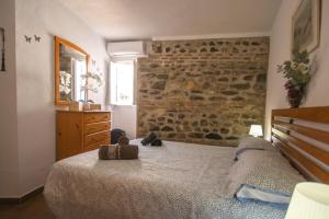 1 dormitorio con cama y pared de piedra en La Casa Del Abuelo, en Vélez-Málaga