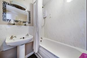 uma casa de banho com um lavatório, um espelho e uma banheira em Iona Inn em Derry Londonderry