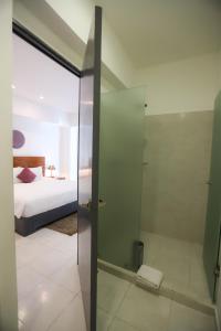 a bathroom with a glass shower and a bed at TRYP by Wyndham Chetumal in Chetumal