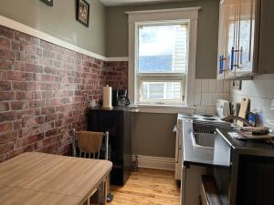 una cocina con una pared de ladrillo y una mesa en Maryland Homestay in Winnpeg downtown en Winnipeg