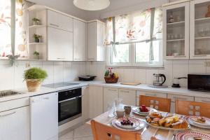 a kitchen with white cabinets and a table with food on it at Casa Valore central with parking by 8essentially in Chania Town