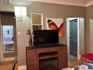 una sala de estar con TV con una mariposa en la pared en Maryland Homestay in Winnpeg downtown en Winnipeg