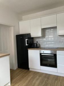 a kitchen with white cabinets and a black refrigerator at Seaferns in Weston-super-Mare