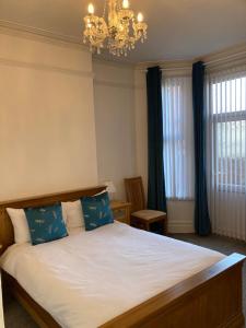 um quarto com uma cama com almofadas azuis e um lustre em Seaferns em Weston-super-Mare