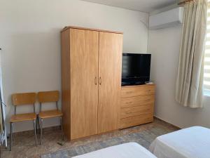a bedroom with a cabinet with a tv and a chair at Apartments in complex Daisy in Kranevo