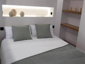 1 dormitorio con 1 cama con sábanas y almohadas blancas en Ospede Luscofusco Carballo-Costa da Morte, en Carballo