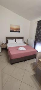 um quarto com uma cama grande e lençóis cor-de-rosa em Anna Maria Apartment em Skala Marion