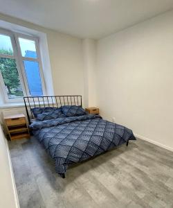 een slaapkamer met een bed met een blauw dekbed en een raam bij Central Apartments Opava in Opava