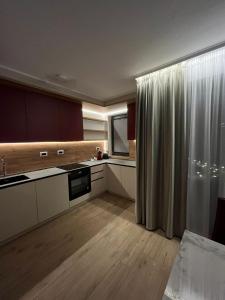 a kitchen with white cabinets and wood floors and a window at Valentini Apartments in Cluj-Napoca