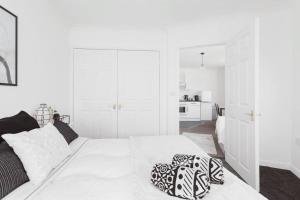 a white bedroom with a bed and a kitchen at The Minimalist - Entire 1 bed flat near Gunwharf Quays, Ground Floor Flat Private Entrance in Portsmouth