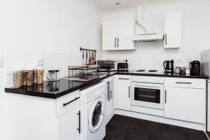 cocina con armarios blancos, lavadora y secadora en The Minimalist - Entire 1 bed flat near Gunwharf Quays, Ground Floor Flat Private Entrance, en Portsmouth