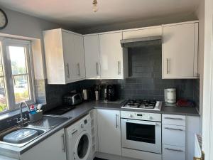 a kitchen with white cabinets and a stove top oven at Luxury Town Centre Apartment in Ipswich