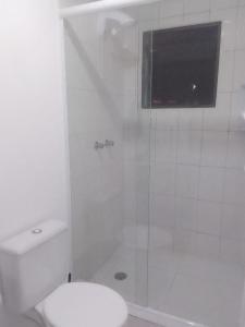 uma casa de banho branca com um chuveiro e um WC. em Apartamento Completo A25 Flat Centro em Mogi das Cruzes