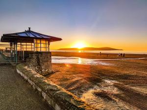 a building on the beach with the sunset in the background at Seaferns in Weston-super-Mare