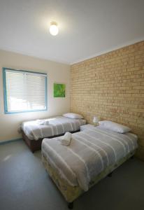 two beds in a room with a brick wall at Coolum Budget Accommodation in Coolum Beach