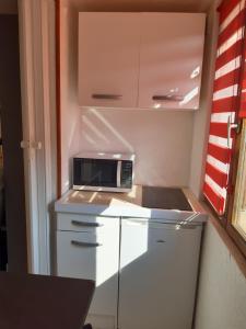 une petite cuisine avec un micro-ondes au-dessus d'un réfrigérateur dans l'établissement Studio indépendant, à Saint-Illiers-la-Ville