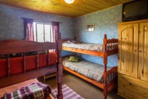 a bedroom with two bunk beds in a cabin at Piuke Mapu Patagonia Hostel in Cholila