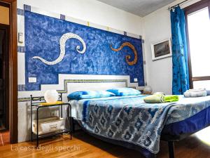 a bedroom with two beds and a blue wall at La Casa Degli Specchi-villetta con due giardini in La Maddalena