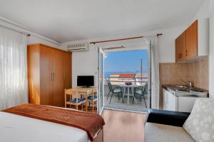 a room with a bed and a kitchen with a balcony at Residence Apartments in Makarska