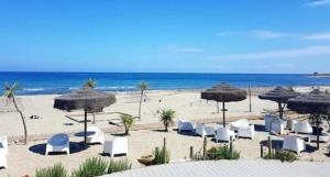 維拉普特祖的住宿－Villetta Porto Corallo，海滩上设有椅子和遮阳伞,还有大海