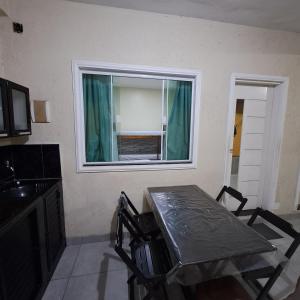 Una mesa y sillas en una cocina con ventana. en Suíte Caminho do Sol, en Arraial do Cabo